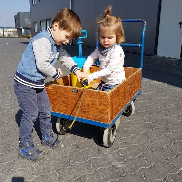 Sohn und Tochter der Familie Ernst spielen mit einem Bollerwagen